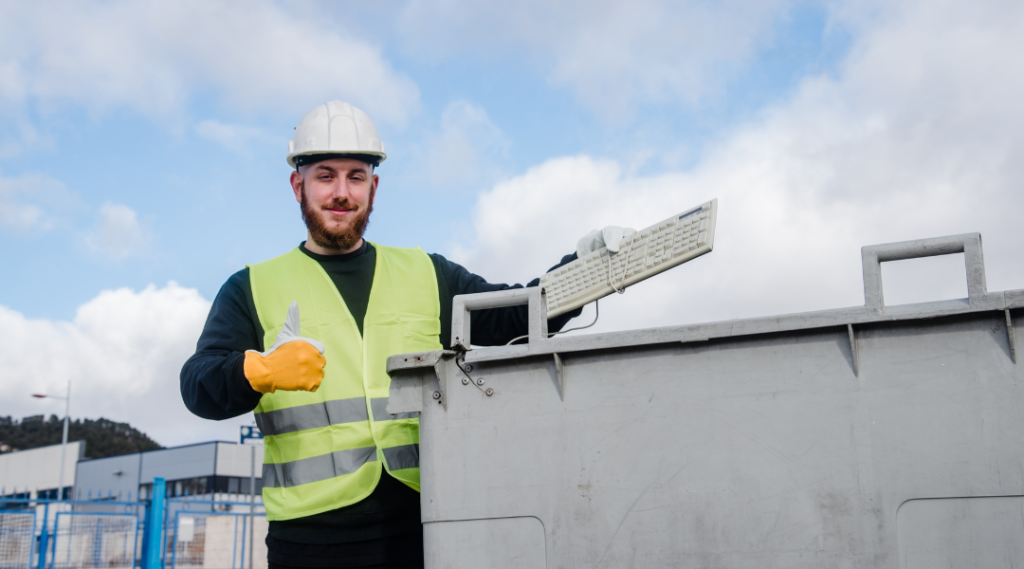 a worker of rental dumpster truck throwing a trash keyboard