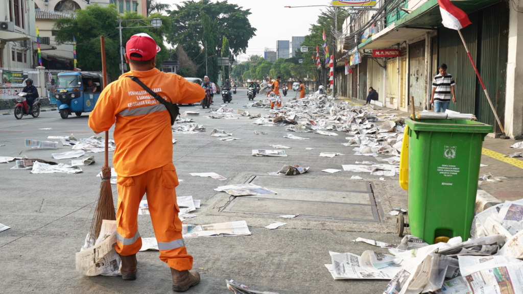 A sanitation worker looking at the paper lying at the road