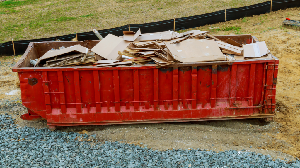 A red rusty metal dumpster full of carton waste