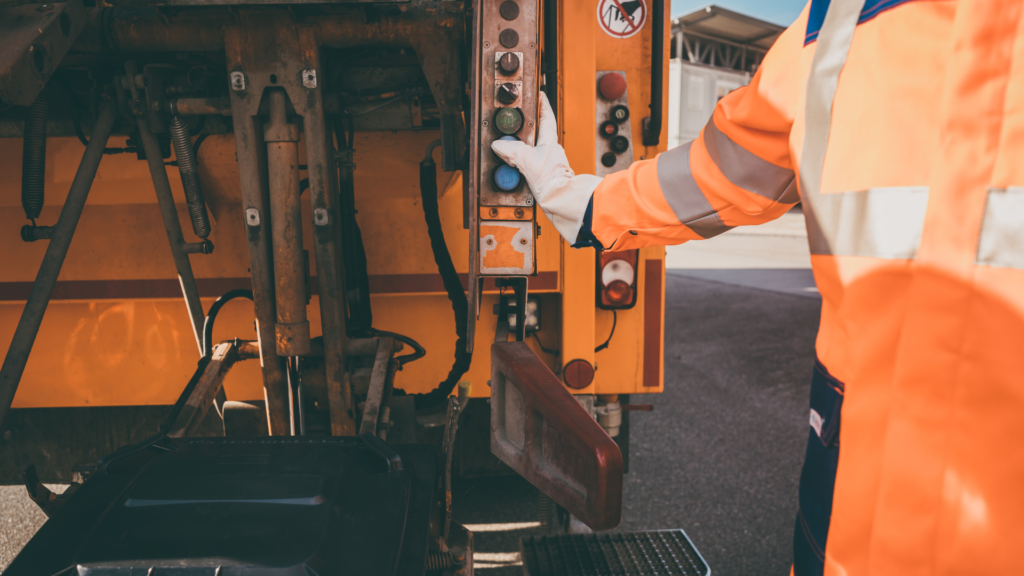 a garbage worker operating a dumpster truck